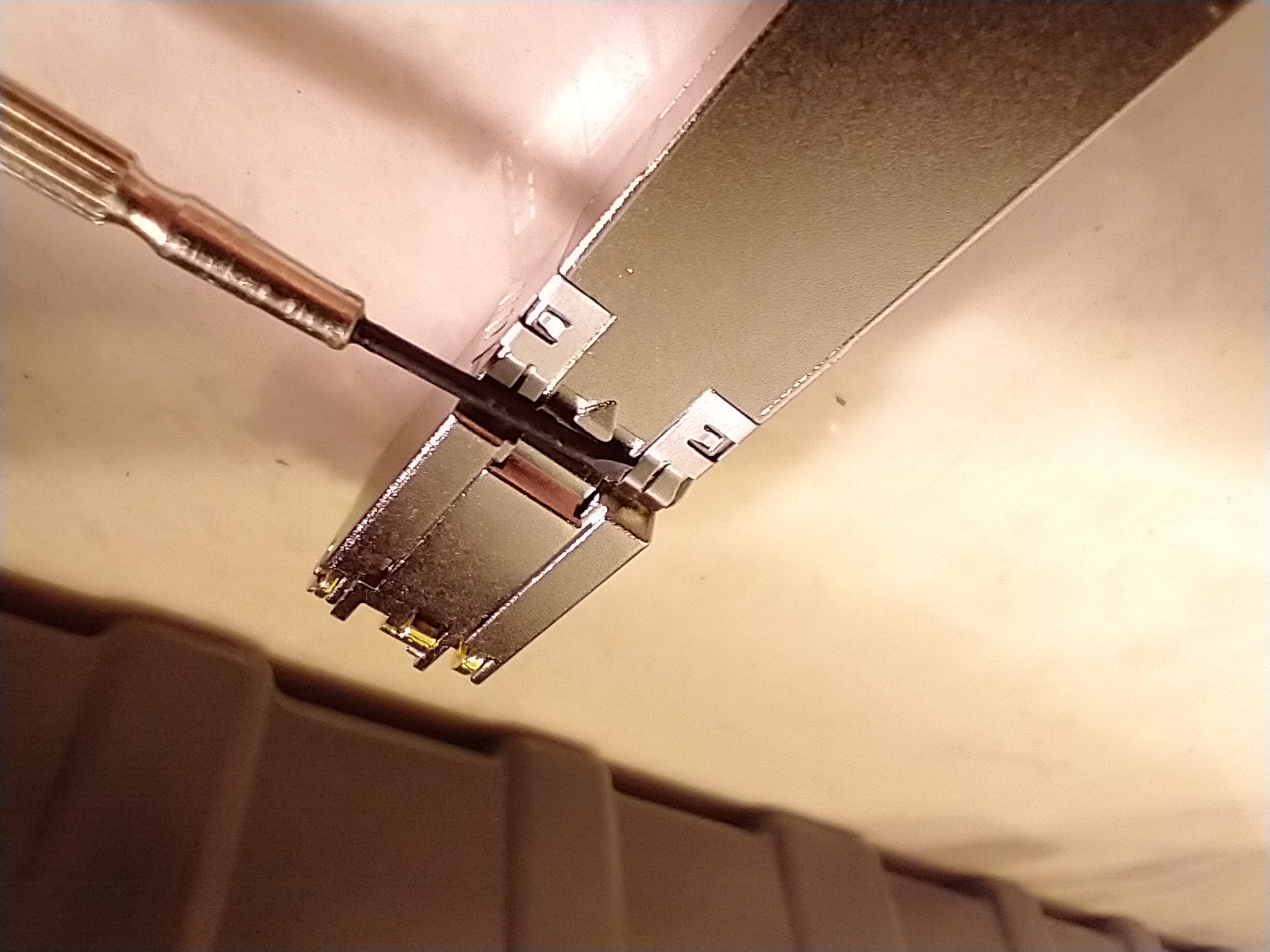 Putting a screwdriver under part of the module's reatainer clip